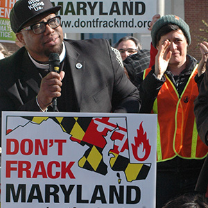 Local activists speak at a rally with a sign saying "Don't frack Maryland"