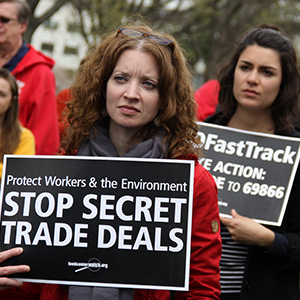 Activists march with signs protesting the Trans-Pacific Partnership trade agreement.