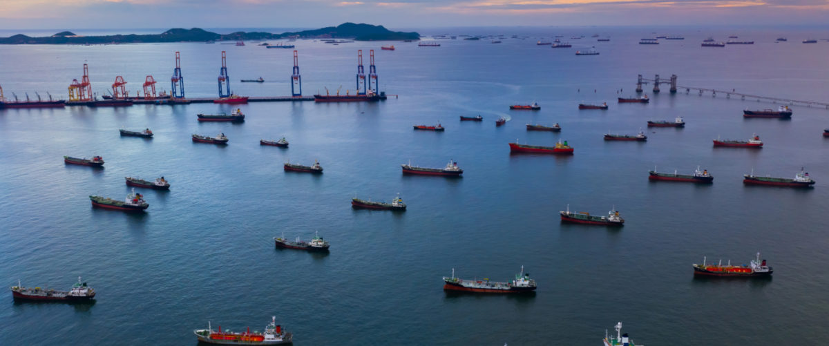 A fleet of ships carrying gas exports sail out of a terminal.