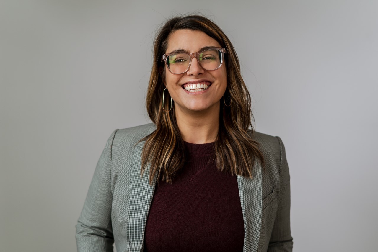 Sara Innamorato smiles in front of a gray background.